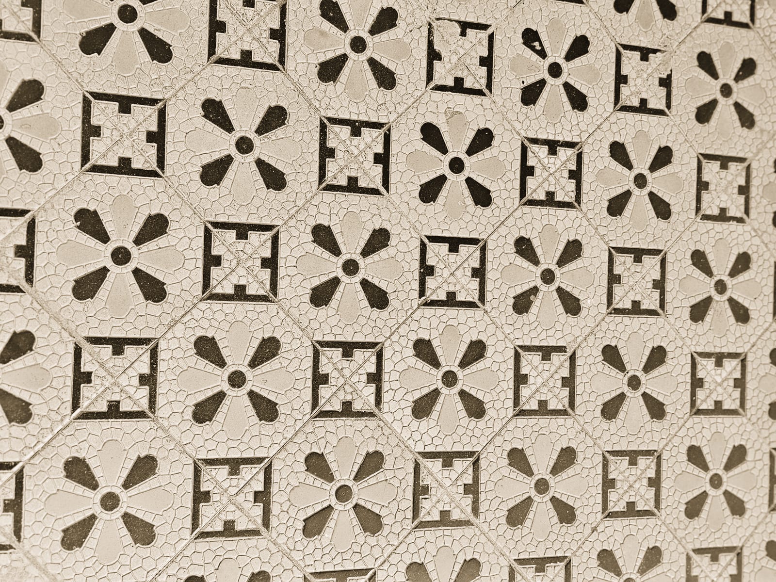 Pavimento a mosaico con un motivo geometrico giallo e nero, consumato dal passaggio.